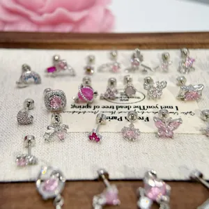 Primo piano di vari simpatici orecchini in acciaio al titanio con cristalli rosa e forme