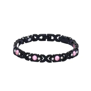 Close-up of black magnetic energy bracelet with pink crystals and stylish XO design
