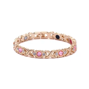 Close-up of a gold-plated magnetic bracelet featuring pink crystals and elegant X motifs
