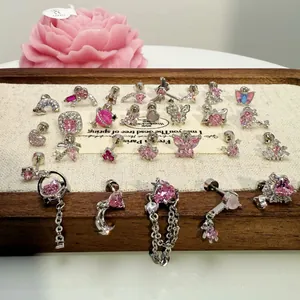 Vasta collezione di orecchini a perno argentati con cristalli rosa su vassoio di legno