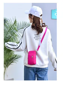 Modell trägt eine magentafarbene Mini-Umhängetasche für Handys über einem weißen Sweatshirt