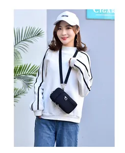 Asiatisches Model mit einer schwarzen, dreilagigen Mini-Stoff-Handytasche als Umhängetasche