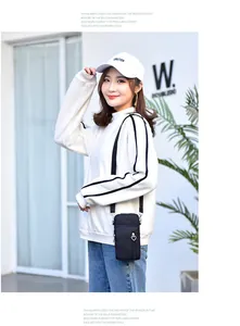 Asiatisches Model mit einer vertikalen schwarzen Mini-Stoff-Umhängetasche für Handys