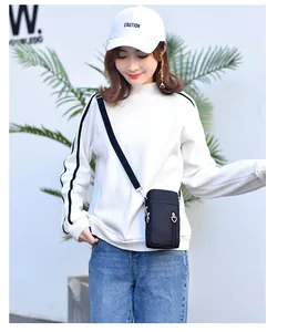 Asiatisches Model trägt eine schicke schwarze Mini-Handy-Umhängetasche mit drei Zips