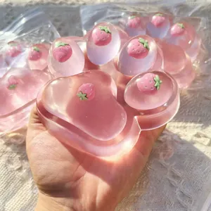 Close-up of translucent pink cat paw squishy toy with strawberry charms inside