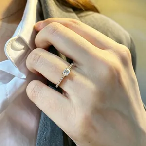 Elegant 18K rose gold ring featuring emerald cut simulated diamond on professional hand