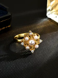 Close-up of gold-plated rotatable ring with faux pearls and floral pattern