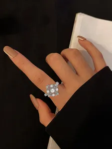 Detailed close-up of an elegant rotatable silver floral ring with white pearls on a finger