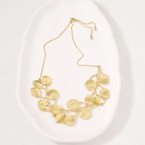 Detailed view of the gold-toned zinc alloy leaf pendant necklace on white tray
