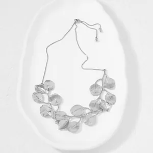 Detailed view of silver-colored zinc alloy leaf pendant necklace on white ceramic
