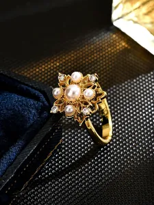 Macro view of an exquisite gold floral ring featuring imitation pearls on a velvet box