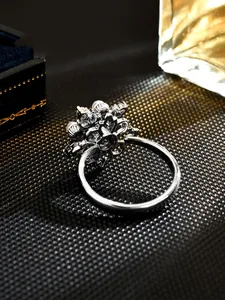 Close-up view of an elegant rotating silver ring with faux pearls and floral design