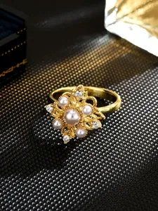 Close-up of elegant gold flower ring decorated with imitation pearls and sparkling crystals