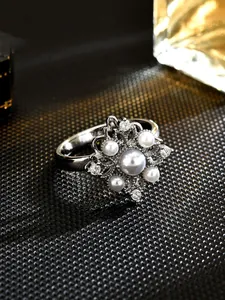 Close-up of rotatable silver-toned floral ring featuring central imitation pearl and crystals
