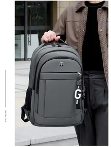 Detail view of grey Oxford cloth backpack with multi-layer zippers and decorative charm