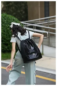 Woman wearing a black gym drawstring backpack with separate shoe compartment outdoors
