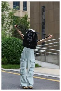 Lightweight black drawstring sports bag with bottom shoe compartment held by a model