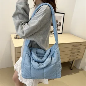 Bolso de hombro acolchado azul grande de tendencia lucido por una modelo con ropa