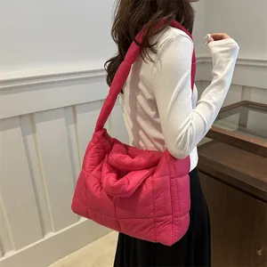 Detalle de un bolso de hombro acolchado rosa ligero usado por una persona en sala
