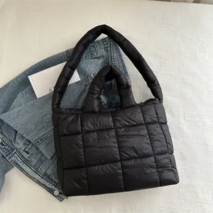 Primer plano de un bolso de hombro acolchado negro con una chaqueta vaquera al fondo