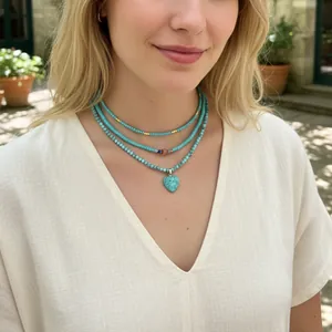 Primo piano di una collana di perle turchesi a strati con ciondolo a cuore su una modella.