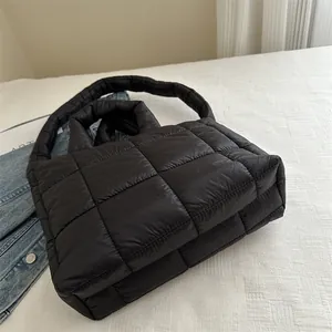 Primer plano de bolso de nube acolchado negro sobre ropa de cama blanca
