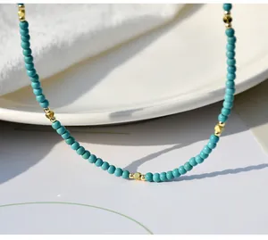 Vista dettagliata di una collana di perle turchesi minimalista con sfere e cubi dorati