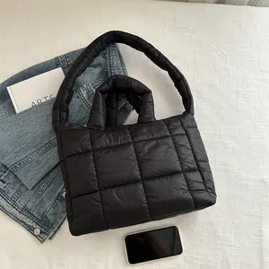 Bolso tote acolchado negro con asas y correa de hombro mostrado con accesorios casuales