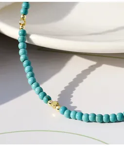 Primo piano dei grani di turchese e degli eleganti accenti in metallo dorato di questa collana