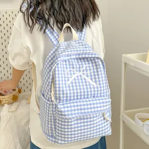 Achteraanzicht van meisje met een blauwe ruitjesrugzak met witte strikborduring.