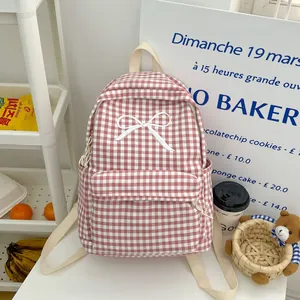 Gedetailleerd zicht op roze geruite rugzak met witte strik en crème schouderbanden.