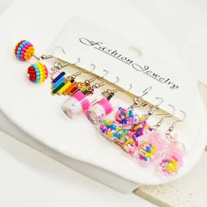 Détail de jolies boucles d'oreilles colorées en résine avec formes d'ours et nourriture.