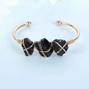Detailed view of handmade gold wire-wrapped cuff bracelet with three raw black stones