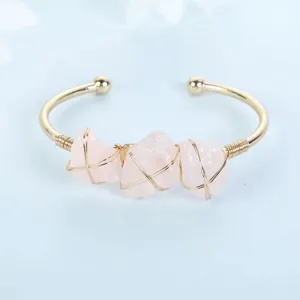 Detail showing raw rose quartz stones wrapped in gold wire on a cuff bracelet.