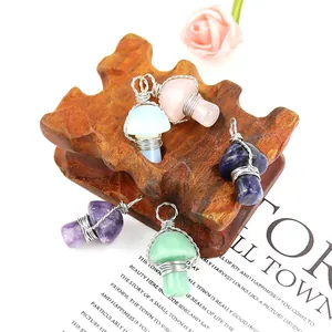 Assorted handmade wire-wrapped natural crystal mushroom pendants on a rustic wood stand
