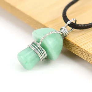 Macro detail of a handmade wire-wrapped green crystal mushroom pendant necklace.