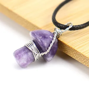 Detail view of a handmade wire wrapped purple crystal mushroom pendant on black cord.