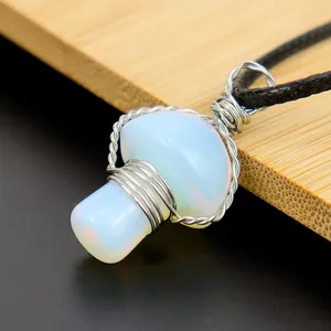 Macro view of handmade silver wire-wrapped mushroom pendant with opalite-like stone.