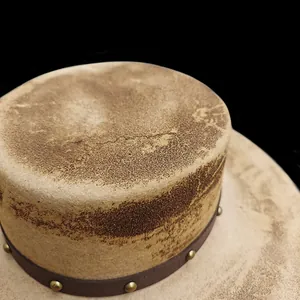 Macro detail of a vintage distressed wool fedora hat with a studded leather band