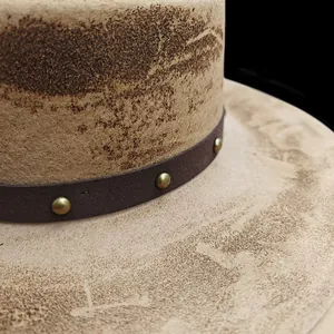 Close-up of a vintage distressed wool fedora featuring a studded leather band texture