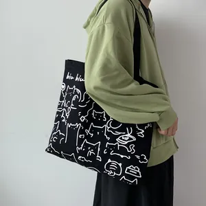 Vista detallada del bolso de lona negra con bonitos estampados de gatos blancos y texto