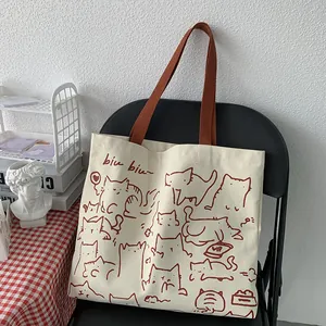 Vista detallada de las ilustraciones de gatos rojos en el bolso de lona blanca con asas