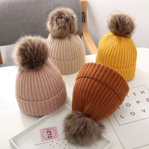Set mit vier gerippten Kinder-Strickmützen mit großen Kunstfell-Pompons in warmen Herbstfarben.