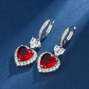 Close-up of heart-shaped garnet red drop earrings with sparkling cubic zirconia accents
