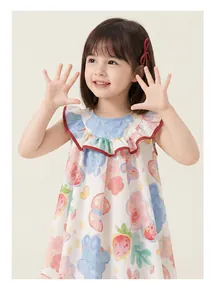 Kleines Mädchen in einem weißen ärmellosen Baumwollkleid mit bunten Obst und Blumengrafiken