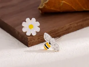 Vue macro détaillée des boucles d'oreilles asymétriques marguerite et abeille avec strass.