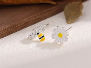 Vue détaillée des boucles d'oreilles asymétriques abeille et marguerite