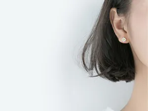 Gros plan détaillé d'une boucle d'oreille en forme de marguerite blanche sur un modèle