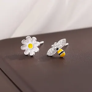 Boucles d'oreilles asymétriques en argent avec marguerite blanche et abeille en cristaux