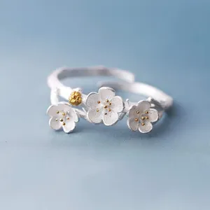 Detail view of a vintage silver open ring with intricate plum blossom flower motifs
